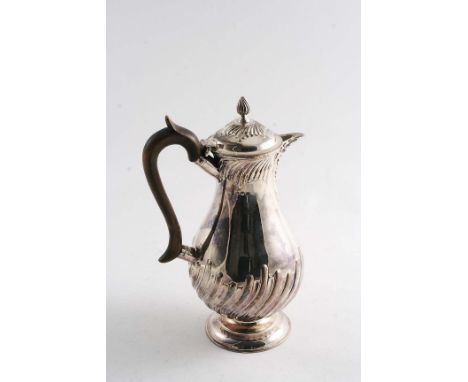A LATE VICTORIAN BALUSTER HOT WATER JUG with an upper & lower friezes of swirl fluting, a leaf-wrapped spout and flame finial