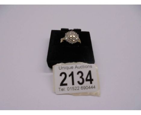 A diamond ring in a cluster design with diamond set shoulders, Hall marked London 1993, Approx .60cts, size R, 5.4 grams.