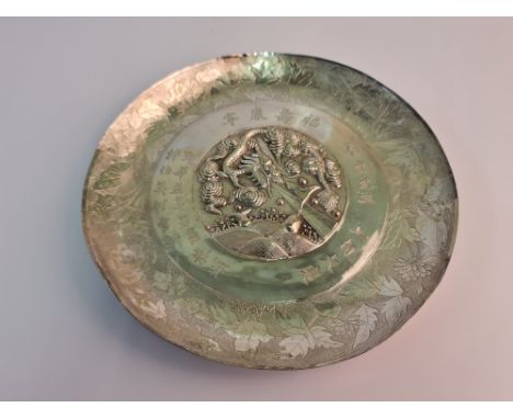 A Chinese presentation plate, featuring central repousse dragon and fish design, surrounded by engraved Chinese character mar