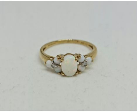 A hallmarked 9ct yellow gold opal and diamond ring, set with a central oval opal cabochon, flanked to either side with three 