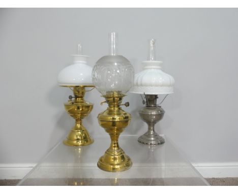 A brass and frosted glass Oil Lamp, the shade with motifs, together with two others similar, tallest 58cm (3) 