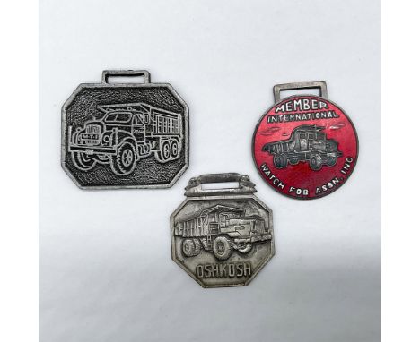 Metal finish with embossed design and lettering. First fob front view: features embossed outline of a dump truck with license