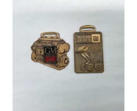 Metal finish with embossed design and lettering. First fob front view: GM General Motors Diesel Power; reverse side: The Sign