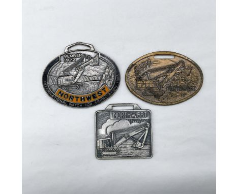 Metal finish with embossed design and lettering. First fob, black and orange enamel over a silver-colored finish, front view: