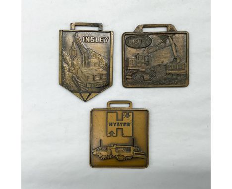 Metal finish with embossed design and lettering. First fob, pentagon shaped, front side: Insley; reverse side: bubble texture