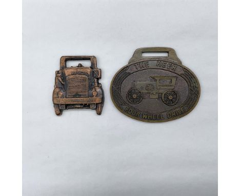 Metal finish with embossed design and lettering. First fob, copper-colored finish, front view: the front side of an Autocar; 