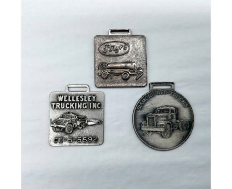 Metal finish with embossed design and lettering. First fob front view: Etnyre; reverse side: blank. Second fob front view: We