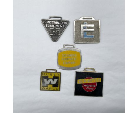 Metal finish with embossed design and lettering. Four of the five fobs are colored enameled. First fob front view: Constructi