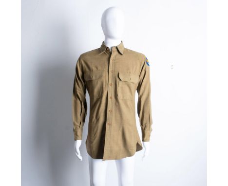 A tan colored shirt with brown buttons and two chest pockets donning the US Army Air Division insignia. Shirt length measures