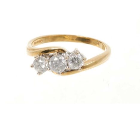 Diamond three stone ring with three brilliant cut diamonds in cross-over claw setting on 18ct yellow gold shank. Estimated to