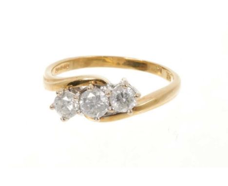 Diamond three stone ring with three brilliant cut diamonds in cross-over claw setting on 18ct yellow gold shank. Estimated to