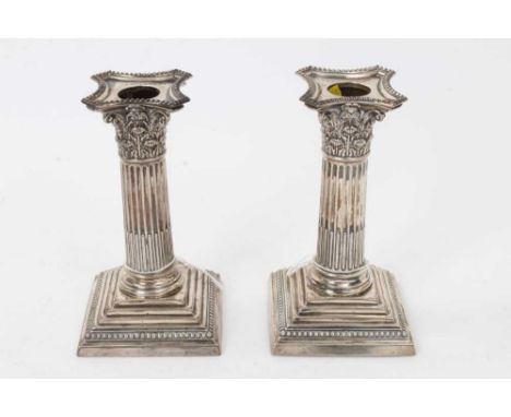 Pair of late Victorian silver Corinthian column candlesticks, on stepped square bases, with separate sconces (London 1900/190