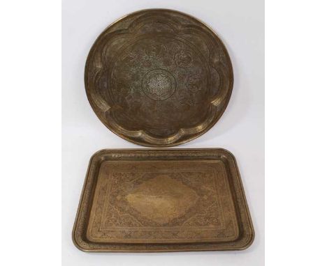 Two Islamic engraved brass trays, the first of circular form, with figural reserves and arabesque ornament, 50cm diameter, th