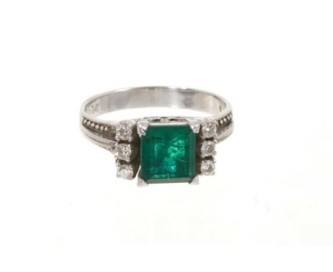 Art Deco emerald and diamond ring with a square step cut emerald flanked by three brilliant cut diamonds to each raised shoul