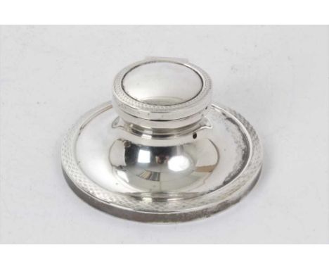 1920s silver capstan inkwell of typical form, with engine turned borders, hinged opening cover and plain glass ink reservoir 