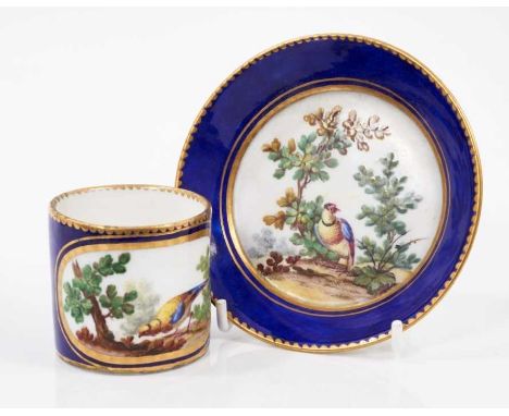 A Sevres coffee can and saucer, 18th/19th century, polychrome painted with birds among foliage, on a gilt-patterned cobalt bl