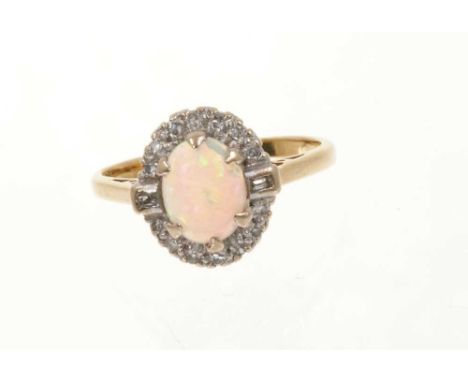 Opal and diamond cluster ring with an oval cabochon opal measuring approximately 8mm x 6mm flanked by two baguette cut diamon