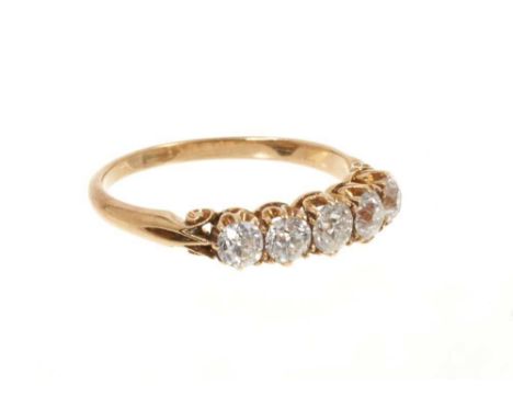 Late Victorian diamond five stone ring with five graduated old cut diamonds in gold claw setting with scroll shoulders on pla