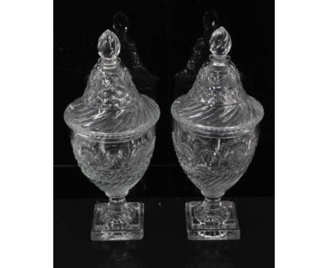 A pair of Regency cut glass covered urns or bonbonnieres, with bands of fluting, diamond and foliate patterns, on square step