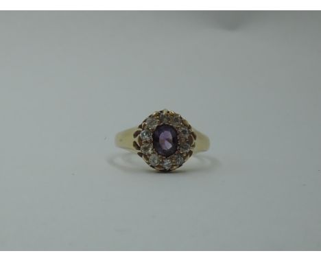 A Victorian amethyst and diamond cluster dress ring having an oval central surrounded by old cut diamonds on an 18ct gold loo