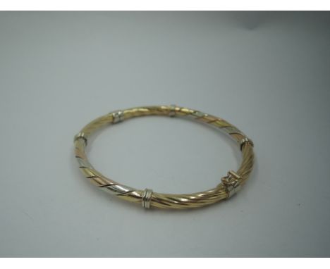 A 9ct triple coloured gold hinged bangle having twist decoration, approx 9.7g