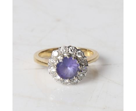 An 18 carat gold, tanzanite and diamond ring, the central round facet cut tanzanite surrounded by a band of diamonds, ring si