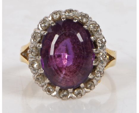 An 18 carat gold amethyst and diamond ring, centred with an oval cut amethyst surrounded by diamonds, ring size K, 7.6 grams