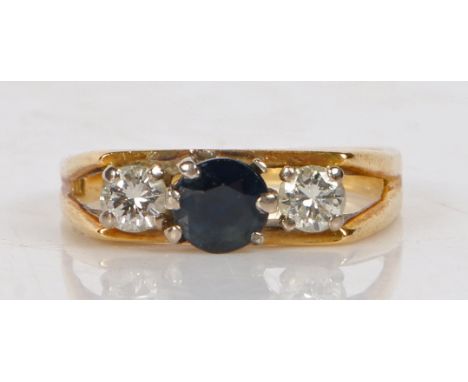 An 18 carat gold sapphire and diamond ring, the central sapphire flanked by two diamonds and pierced shoulders, ring size K, 