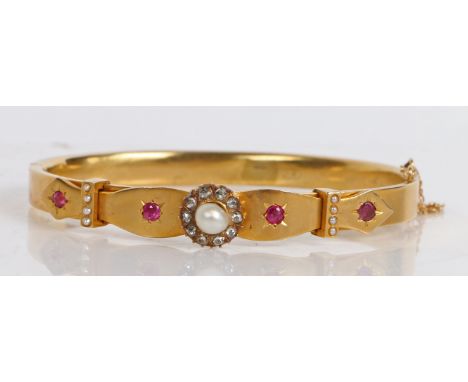 A Victorian yellow metal, pearl, diamond and ruby bangle, with central pearl surrounded by a band of diamonds, flanked by fou
