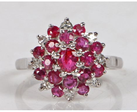 An 18 carat white gold, ruby and diamond cluster ring, the central ruby surrounded by a band of diamonds and a further band o