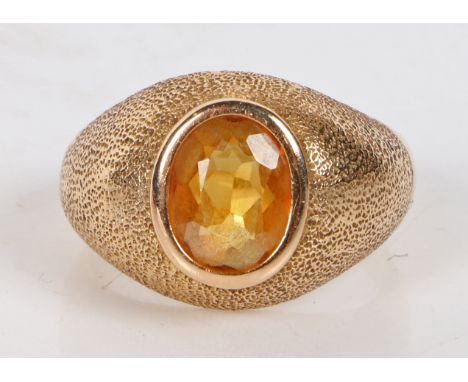 An 18 carat gold and citrine ring, the oval facet cut citrine housed in a beaten effect mount, ring size R, 6.7g