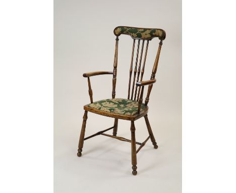 A stained beech framed open armchair, late Victorian in vernacular style with padded top rail and four spindles to the back o