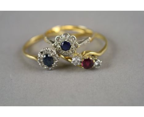 A three stone ruby and diamond ring, the shank stamped '18ct', together with an oval sapphire and diamond cluster ring, stamp