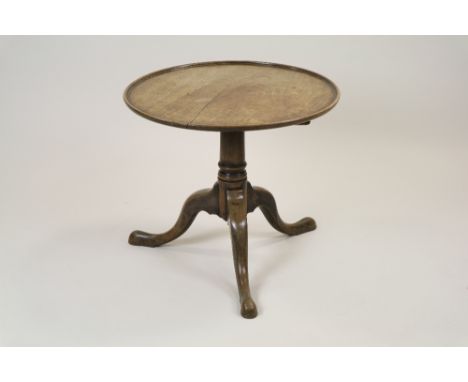 A George III style mahogany tripod table the circular dished top tilt top on a squat column, three down curved legs and pad f