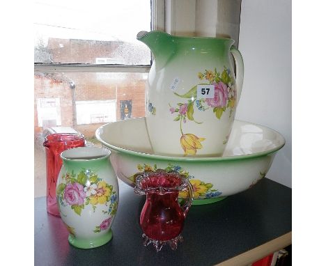 Two cranberry glass vases and a floral patterned jug and basin