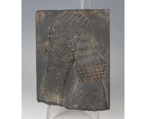 An Assyrian carved basalt plaque, possibly 900-600 BC, finely carved in low relief with a profile portrait of the King of Ass