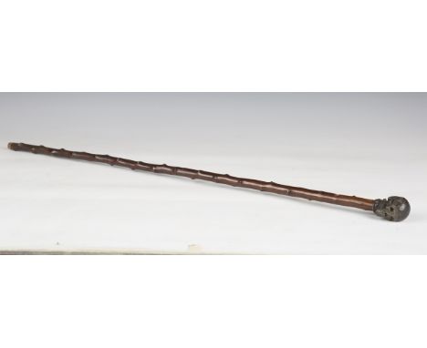 An early 20th century walking cane, the cast metal handle modelled in the form of a skull, length 87cm.Buyer’s Premium 29.4% 