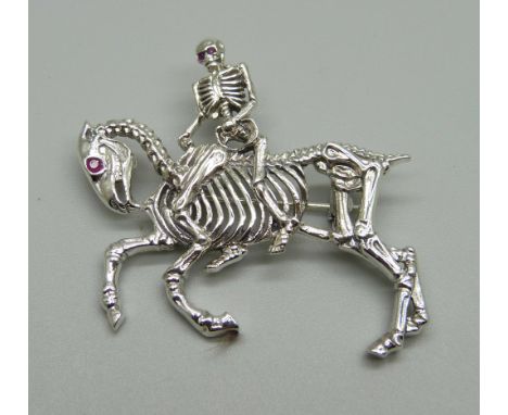 A silver brooch depicting a skeleton riding a horse, set with ruby eyes, 11g, 47mm 