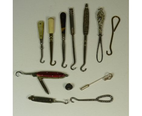 A small folding button hook/knife with red enamelled casing together with other small button hooks, tape threader, a small bu