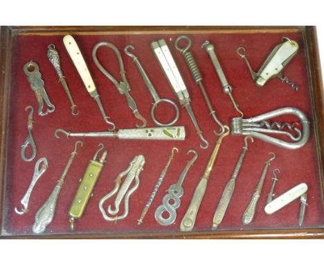 A display of 22 assorted button hooks, includes folding examples with combined corkscrew; silver handled and combined hook an