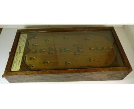 A "Migatelle" bagatelle game, with glass top and in oak case, 54cms x 28.5cms ++good