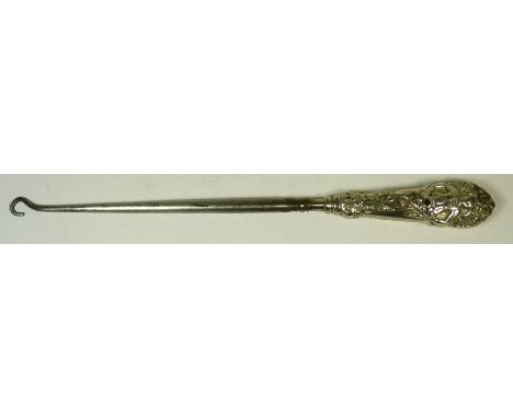 A Victorian button hook with decorative silver handle embossed with female figures and foliate decoration and inset with red 