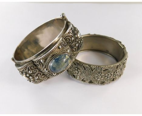 BANGLES. An ornate silver bangle, set with two polished stones, width 2.8cm &amp; a white metal bangle.