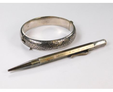 SILVER BANGLE ETC. A silver hinged bangle with engraved front &amp; a silver propelling pencil.