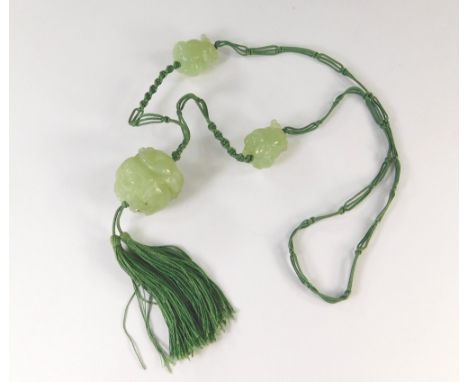 JADE NECKLACE. A late 19th century celadon jade carved necklace, on woven cord.
