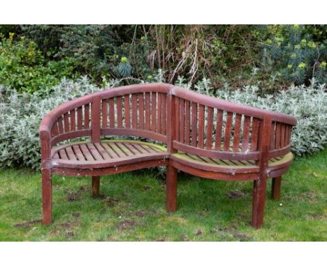 A CURVING TEAK KISSING BENCH 184cm wide x 94cm high Condition: weathered, deterioration to the varnished finish, structurally