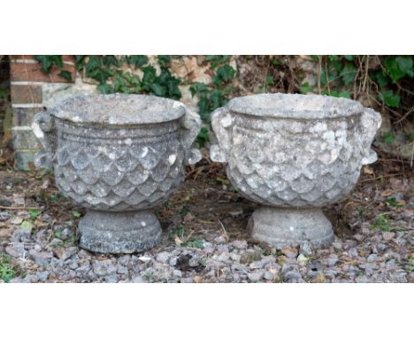 A PAIR OF SMALL CARVED STONE URNS with scrolling handles and fish scale ornament to the bowls and on turned bases, each 34cm 