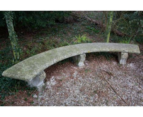 A CURVING STONE GARDEN BENCH with three acanthus leaf carved scrolling supports, 288cm wide overall x 39cm high, the bench to