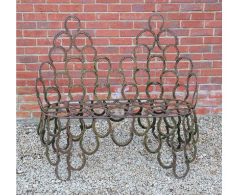 A WROUGHT IRON GARDEN BENCH constructed from horseshoes, 124cm wide x 52cm deep x 112cm high Condition: weathered, rusted sur