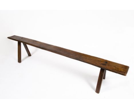 AN OLD, POSSIBLY 18TH CENTURY, ELM BENCH OR FORM with moulded edge and on splayed rectangular section legs, the top 258cm lon